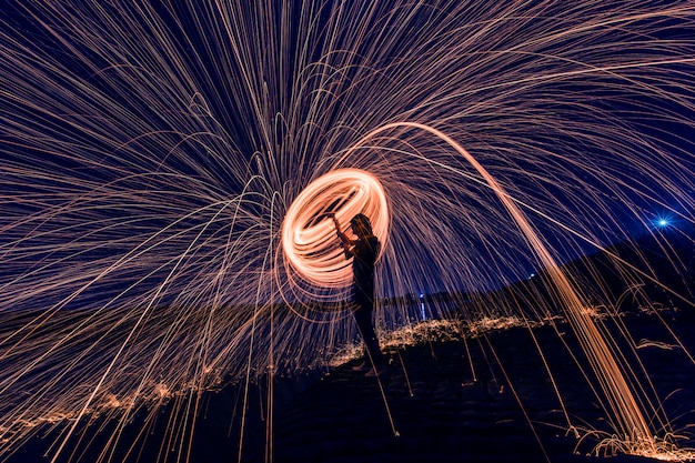 Silhouette of man making a circle of sparks at night