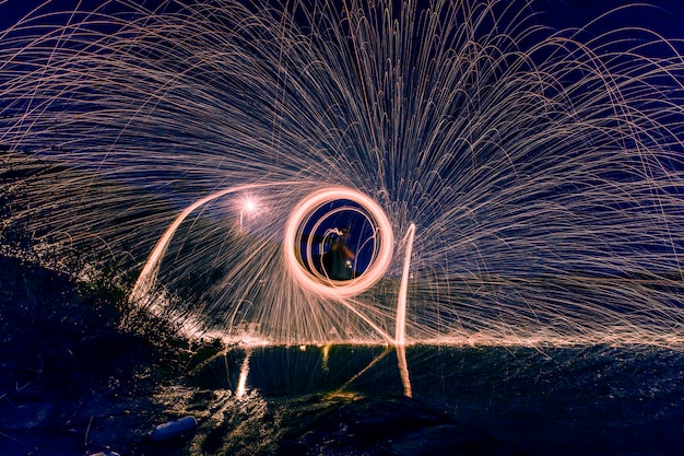 Silhouette of man making a circle of sparks at night