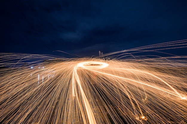 Silhouette of man making a circle of sparks at night