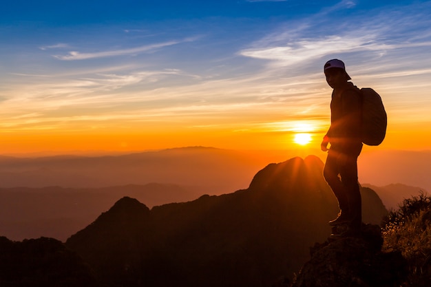 Silhouette of a man on a mountain top. Person silhouette on the rock. 