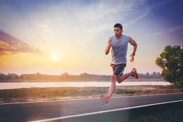 Silhouette of man running sprinting on road. Fit male fitness runner during outdoor workout 