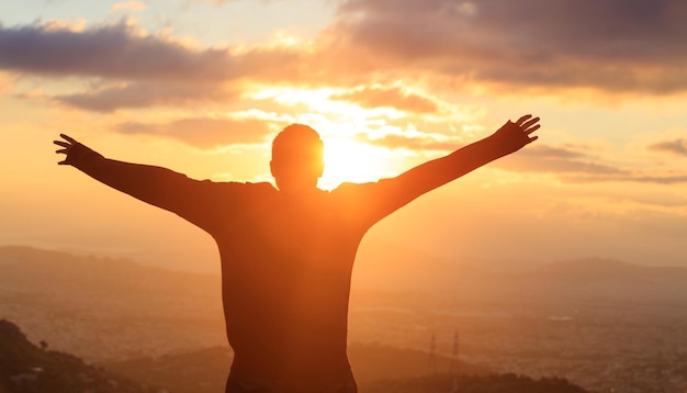 Silhouette of a man standing alone on the top of a mountain