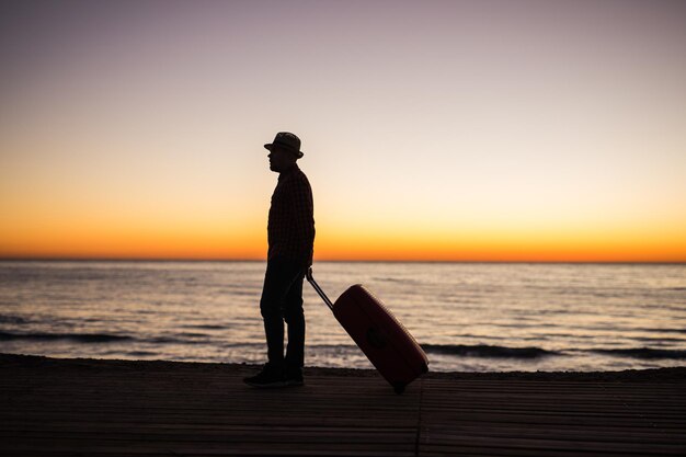 Photo silhouette man standing on beach against sky during sunset