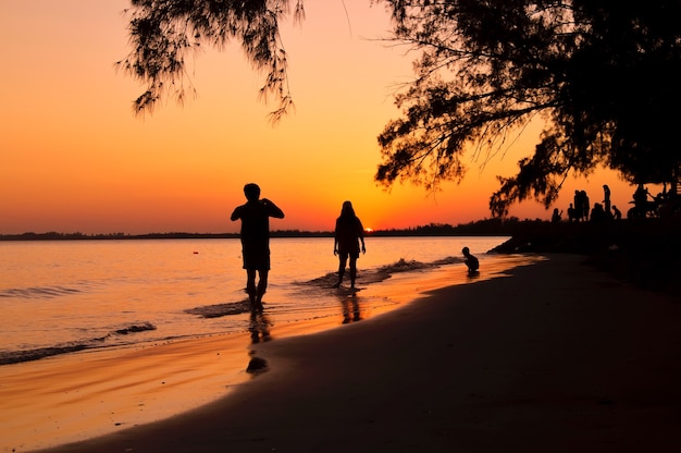 Silhouette of man taking picture his girlfriend on the beach at sunset