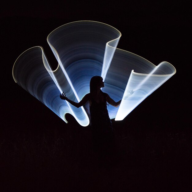 Photo silhouette man with arms raised standing against black background