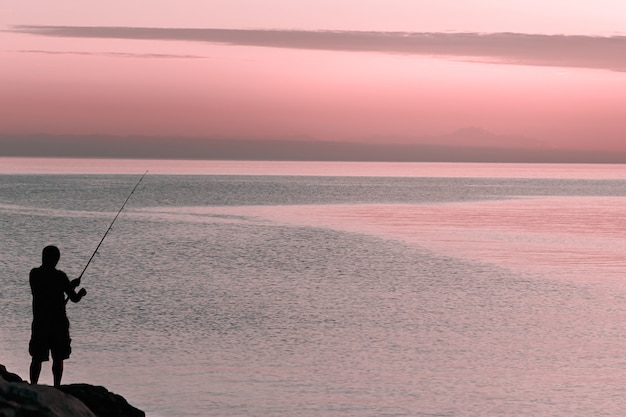 Silhouette of man with fishing spinning