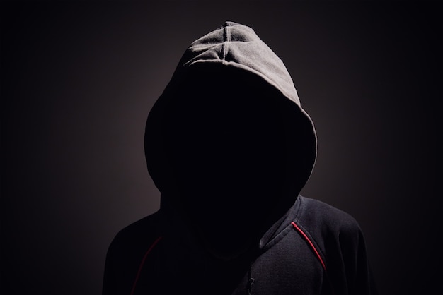 Silhouette of man without face in hood on a black.