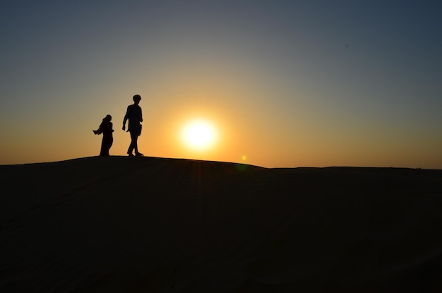 Photo silhouette men and women on landscape against sky during sunset