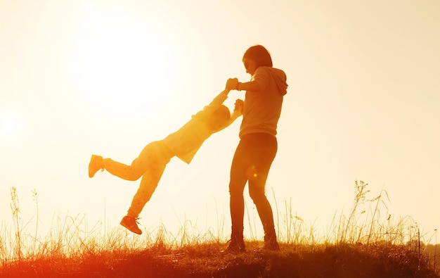 Silhouette of mother and little daughter at sunset