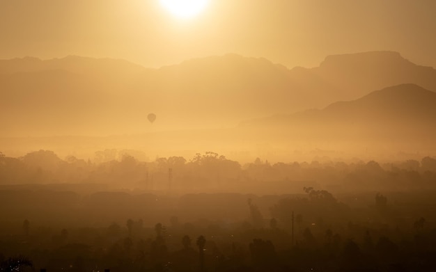 Silhouette of mountains and forest under the vivid sunset yellow sky