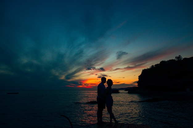 Silhouette of a newlywed couple at the sea at sunset wedding in