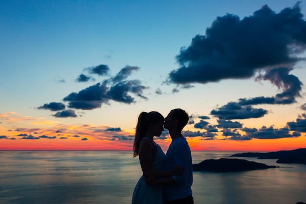 Silhouette of a newlywed couple at the sea at sunset wedding in