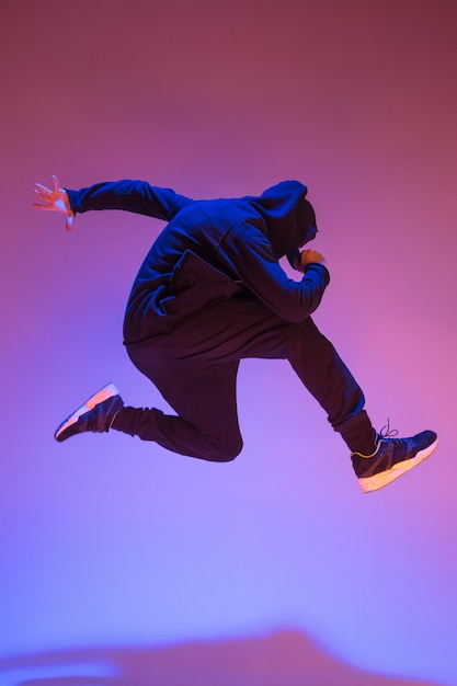 The silhouette of one hip hop male break dancer dancing on colorful background