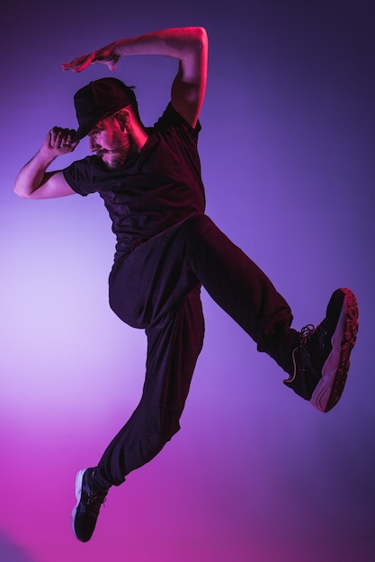 The silhouette of one young hip hop male break dancer dancing on colorful background