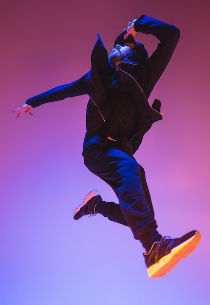 The silhouette of one young hip hop male break dancer dancing on colorful background