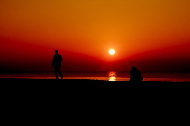 Photo silhouette people at beach during sunset