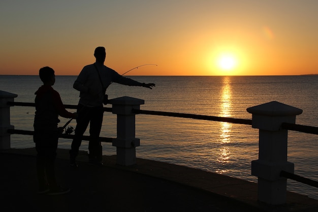 Silhouette of people fishing with the yellow color of the sunset