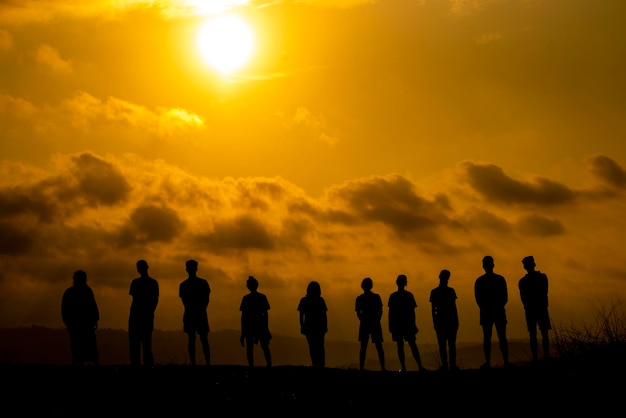 Silhouette people standing on land against cloudy sky during sunset