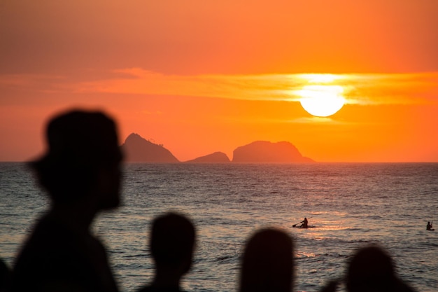 Silhouette of people watching the sunset at arpoador beach in rio de janeiro brazil