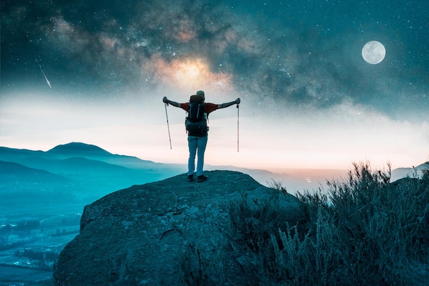 silhouette of a person on a mountain top celebrating his achievement with open arms