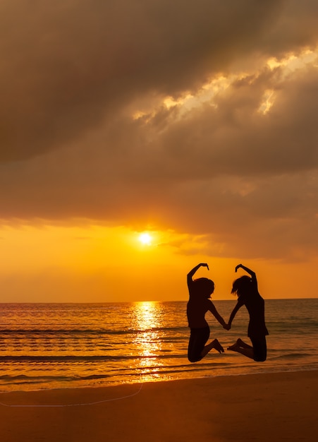 Silhouette photo of love symbol from a couple on the beach at sunset