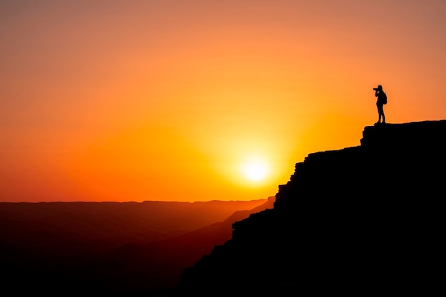 Silhouette  photographer who shoots a sunset in the mountains. Photographer concept