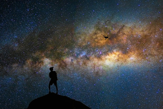 Silhouette of photographer with drone over the milky way on the dark sky