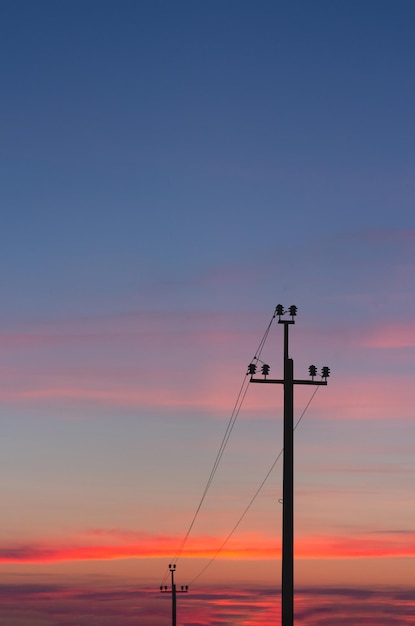 Silhouette of power lines against the background of a bright sunset, high-voltage wires