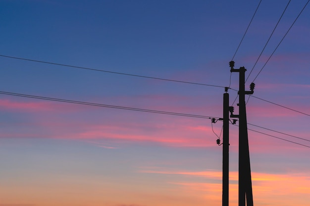 Silhouette of power lines against the background of a bright sunset, high-voltage wires