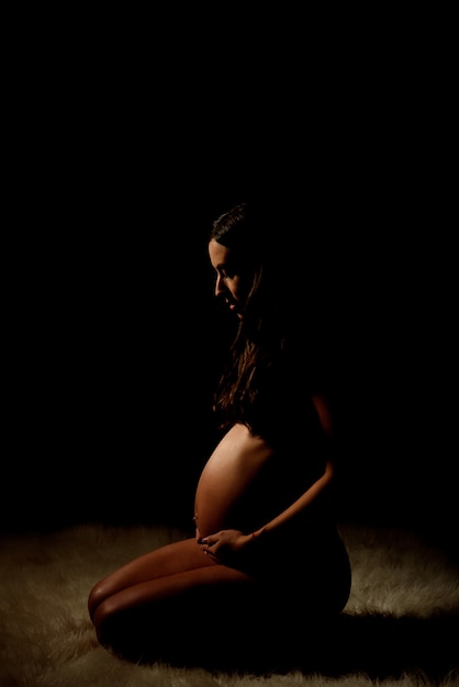 Silhouette of pregnant woman in the dark