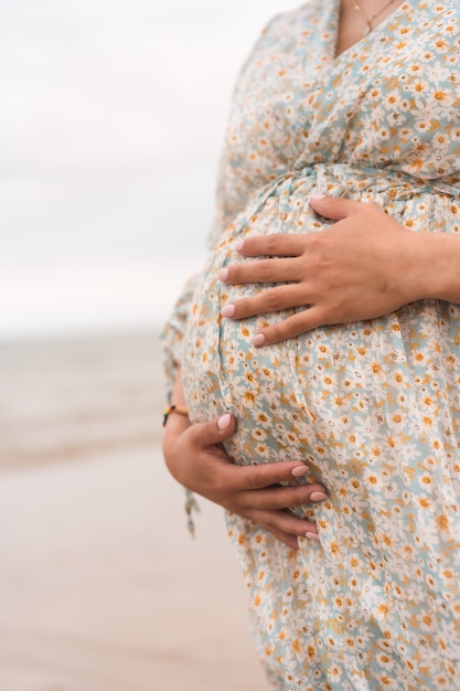 Silhouette of a pregnant woman in a white dress on the beach, pregnant session of a new pregnancy