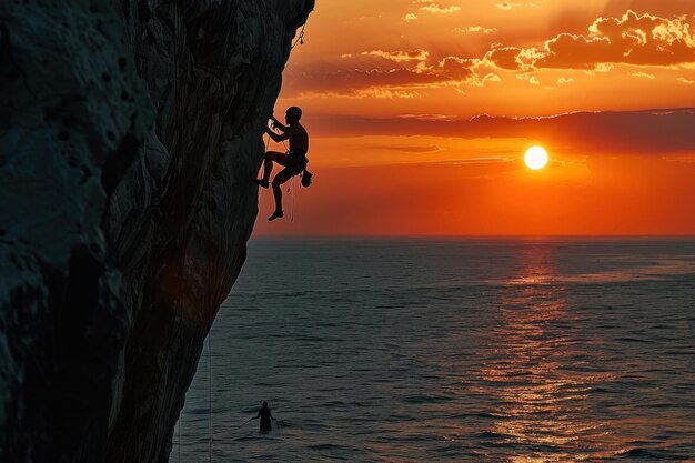 Silhouette of a rock climber scaling cliff face at sunset over water