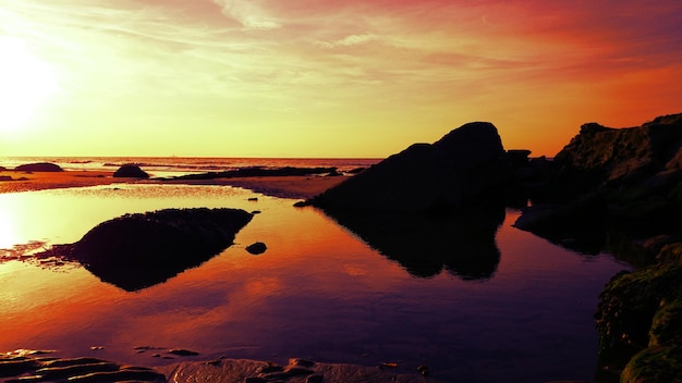 Photo silhouette rocks in sea during sunset