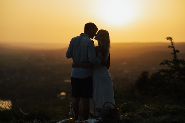 Silhouette of romantic couple kissing while standing on a hill