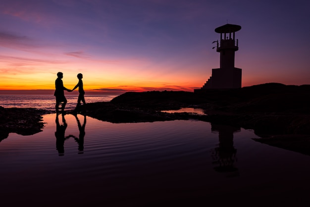 Silhouette Romantic couple with lighthouse at sunset time