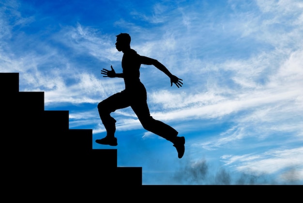 Silhouette of runner on the stairs up against the sunny sky