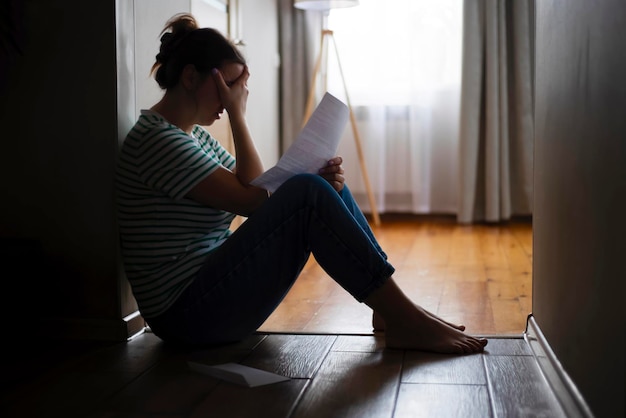 Silhouette of sad and depressed woman sitting on the floor at home