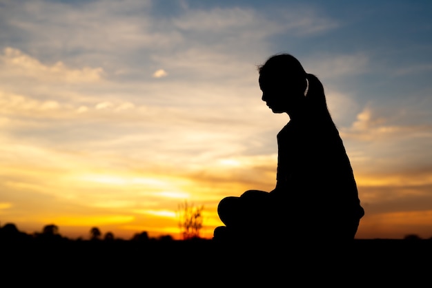 Silhouette of sad and depressed women sitting at walkway of park with sunset