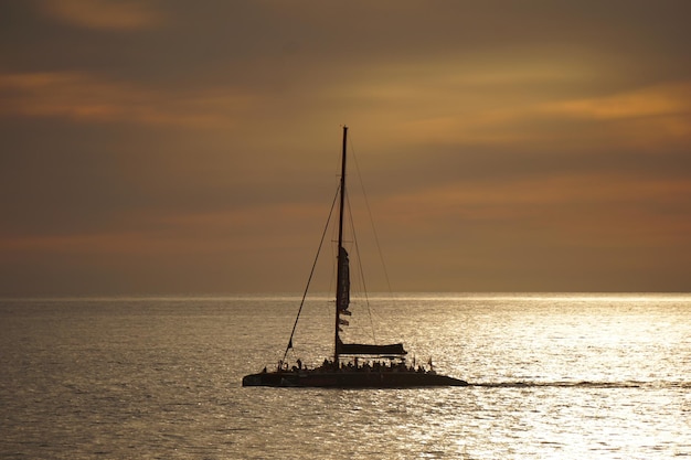 Silhouette sailboat sailing on sea against sky during sunset