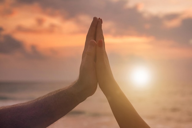 Silhouette sign hands of couple are lovely together at sunset of through Woman and man hands in together sign shape with sunrise and sea ocean background