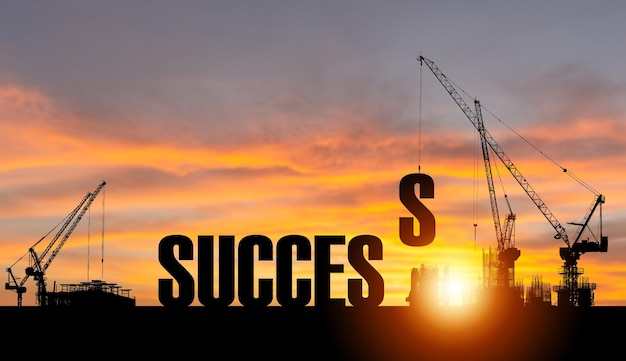 Silhouette of Success on construction site with crane sunset sky for preparation business concepts