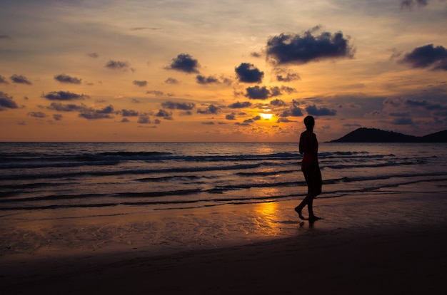 Silhouette sunset with girl walking on beach