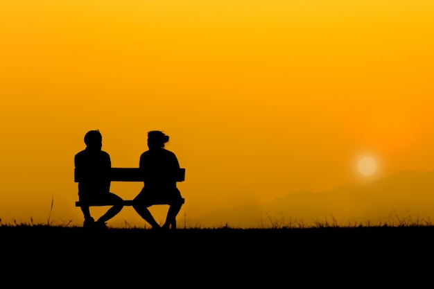 A silhouette of sweetheart on the bench in sunset