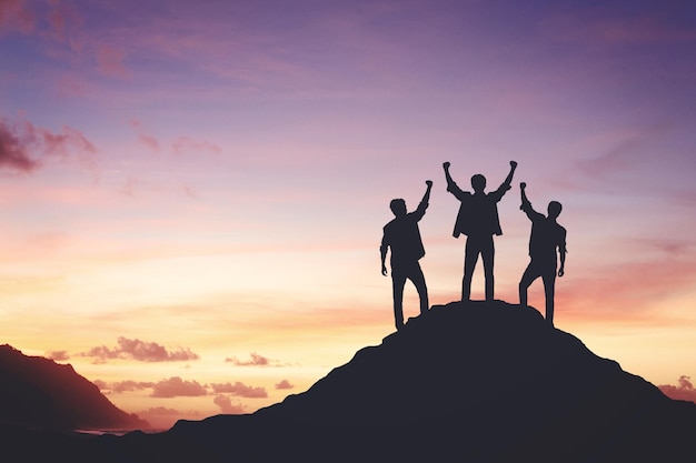 Silhouette of a team celebrating a victory against sunset background concept of leadership