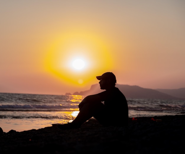 Silhouette teen sitting at the beach in peace