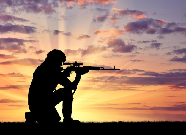 Silhouette of a terrorist with a weapon against a background of a sunset