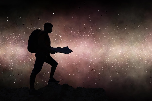 Silhouette travelling backpacker holding map on rocky mountain against milky way galaxy background