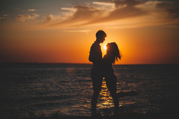 Silhouette of two people holding hands against the sea