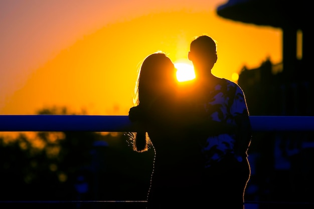 Silhouette of two people in love against the backdrop of the setting sun Romance in relationships and nature