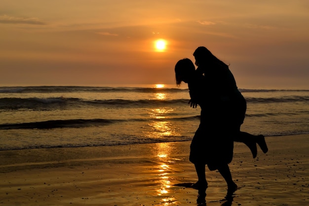 Silhouette of two women playing on the seashore at sunset Golden hour